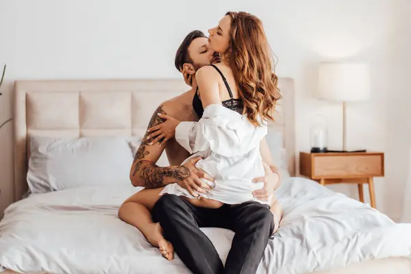 Tutkulu genç bir adamın portresi gözlerini kapatan öpüşen ve güzel baştan çıkarıcı bir kadının yatakta oturması. Cinsellik, tutku konsepti