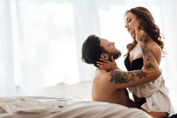 Seksi siyah iç çamaşırlı, seksi genç bir kadının portresi yakışıklı kaslı bir adamı kucaklıyor yerde oturuyor, birbirine bakıyor. Cinsellik, tutku konsepti