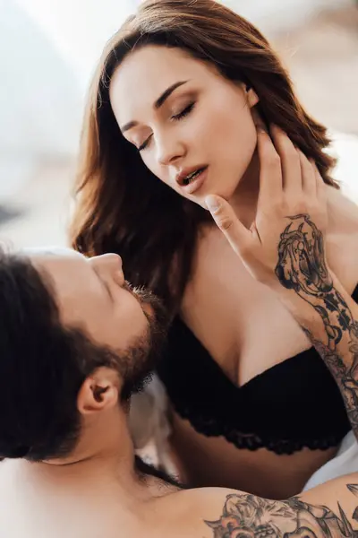 Dantel iç çamaşırlı, baştan çıkarıcı genç bir kadının boynuna dokunan adamın dikey portresi. Kapatın. Cinsellik, tutku konsepti