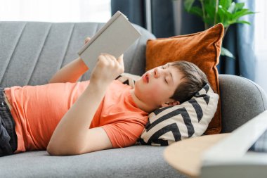 Down sendromlu bir genç evinde kitap okurken rahat bir kanepede uzanıyor. Öğrenme kavramı