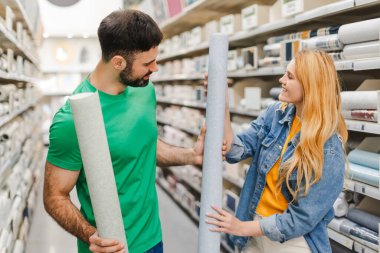 İnşaat mağazasından almak için duvar kağıdı seçen mutlu genç bir çiftin portresi. Alışveriş konsepti