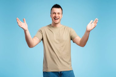 Gülümseyen mutlu adam, mutlu, sevinçli, mavi arka planda soyutlanmış. Kollarını aç, hoş geldin. Selamlama konsepti