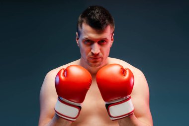 Ringde kırmızı eldiven tutan kendine güvenen boksör, yoğun bakışlar güç ve kararlılık saçan, mavi arka plan gücü ve odaklanmayı vurgulayan