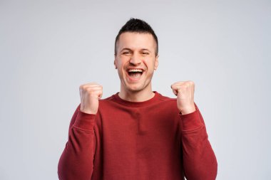 Coşkulu, başarılı adam, kazanan el ele tutuşuyor, kameraya bakarak para kazanıyor, gri arka planda tek başına duruyor. Zafer konsepti