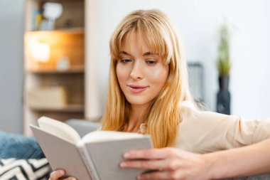 Genç bayan evde rahat bir kanepede dinlenirken ilginç bir kitap okuyor, sakin ve huzurlu bir öğleden sonranın tadını çıkarıyor. Bilgi kavramı