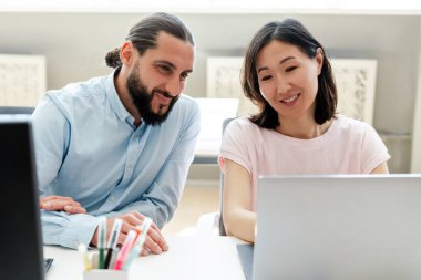 İki profesyonel kadın ve erkek bilgisayar ile parlak ofis alanında iş birliği yapıyorlar. Doğal ışık ve pozitif enerjiyle dolu. Gündelik ama profesyonel atmosferde çeşitli takım planlama stratejileri