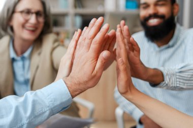 Çeşitli iş adamları bir ofis ortamında takım çalışması ve birlik göstererek başarıyı kutluyor. Gülen, mutlu yüzler güven ve dostluğu yansıtır. İş konsepti
