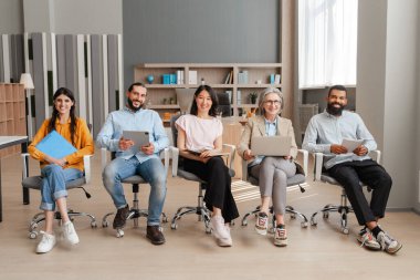 Ofis toplantısında çeşitli, çok uluslu profesyonellerden oluşan bir ekip, ellerinde belgeler ve kameraya bakan dijital cihazlarla koltuklarda oturuyorlar. Takım çalışması konsepti, başarılı iş