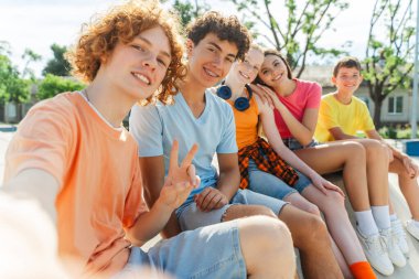 Gülümseyen, çekici gençler şık renkli tişörtler giyip merdivenlerde kameraya bakıyorlar. Üniversite arkadaşları buluşması, iletişim, poz verme. Arkadaşlık kavramı