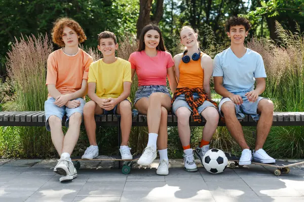 Futbol toplu arkadaş canlısı gençlerin portresi, kaykaylar parkta sırada kameraya bakarak oturuyorlar. Çocukların arkadaşlık konsepti