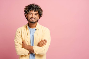 Pembe arka planda kollarını kavuşturup gülümseyen, mutluluk ve başarı saçan kendinden emin bir adam. Canlı bir yaşam tarzı olan modaya uygun bir milenyum. Kopyalama alanı çok