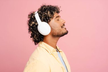 Immerse in music with wireless noise-cancelling headphones on a vibrant pink background. Feel the sound quality, eyes closed in bliss. Transport to relaxation with this modern accessory clipart