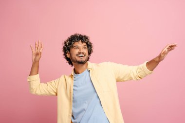 Neşeli genç Hintli adam enerjik bir stüdyoda dans eder. Pembe bir arka planı vardır. Mutluluk ve kaygısız bir ruh yayar.