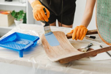 Samimi atölyedeki eski sandalyeyi restore eden, koltuğu özenle maviye boyayan yetenekli bir kadın. Mobilya yenilemesinde yaratıcılığı göstermek, eve klasik stil eklemek