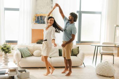 Mutlu genç çift, Asyalı kadın ve Hintli adam modern oturma odalarında dans edip eğleniyorlar. İlişki kavramı