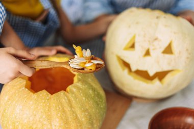 Cadılar bayramı için balkabağı oyan çocuklar, sıcak bir sonbahar ortamında aile olarak eğlenmek ve yaratıcı olmak, seçici odaklanma, el yapımı konsept