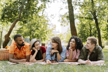 Neşeli gülümseyen çok ırklı arkadaşlar konuşuyor, iletişim kuruyor, Green Park 'ta buluşuyorlar. Erkekler ve kadınlar çimlerin üzerinde yatıyor. Arkadaşlık kavramı