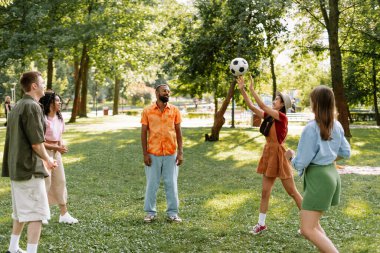 Bir grup genç, çok uluslu insan parkta futbol oynuyor, boş zaman, piknik konsepti