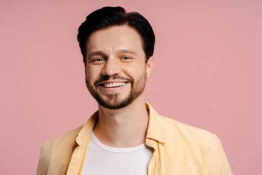 Yakışıklı, çekici bir adam, pembe arka planda gülümseyen erkek manken kameraya bakıyor, yakın plan. Reklam kavramı