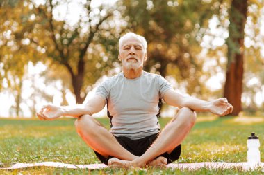 Son sınıf öğrencisi, meditasyon için parkta yoga yapıyor yoga minderinde gözleri kapalı oturuyor. Denge, uyum kavramı