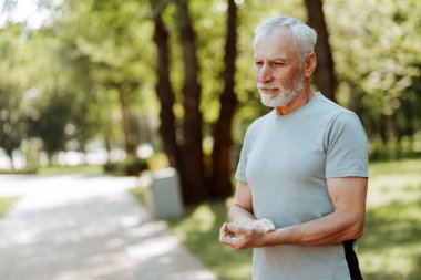 Ciddi kıdemli bir adam dışarıda egzersiz yaparken nabzını kontrol ediyor, kopyalama alanı. Sağlık hizmetleri, aktif yaşam tarzı kavramı