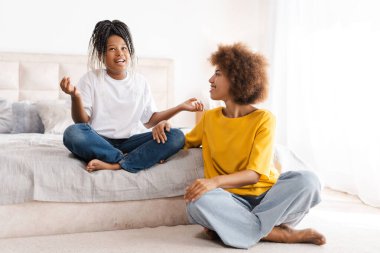 Mutlu melez anne ve küçük kız evde meditasyon yapıyorlar. Çocukluk, annelik, aile kavramı.