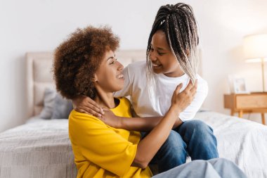 Afro-Amerikan anne ve genç kızın portresi evde birlikte vakit geçirip, kucaklaşmaları. Çocukluk, annelik, aile kavramı.