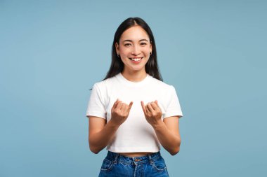 Küçük parmakları olan genç bir Asyalı kadın mavi arka planda izole bir şekilde kameraya bakıyor. Vücut dili kavramı