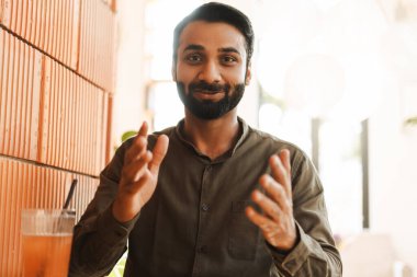 Çekici Hintli blogcu portresi, video kaydı, kameraya bakmak. Ofiste çalışan başarılı Hintli adam video konferansı yapıyor. Çevrimiçi iş, uzak iş