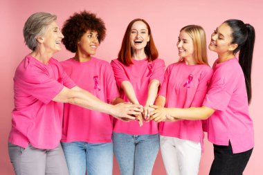 Pembe kurdeleli pembe tişörtler giyen beş farklı kadın el ele tutuşup gülümsüyor ve meme kanseri farkındalığını destekliyorlar.
