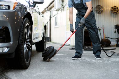 Tamirci garajda araba kaldırmak için hidrolik kriko kullanıyor. Mevsimlik lastik değişimine hazırlanıyor.