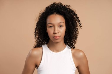 Bej arka planda izole edilmiş kameraya bakan güzel bir Afrikalı Amerikalı kadının portresi. Reklam, alışveriş konsepti