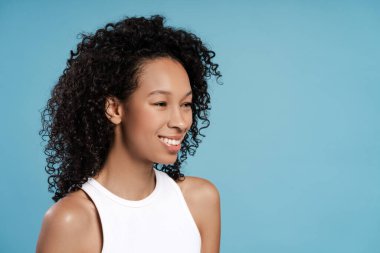 Gülümseyen Afrikalı Amerikalı kadının portresi mavi arka planda fotokopi alanına bakıyor. Reklam, alışveriş konsepti