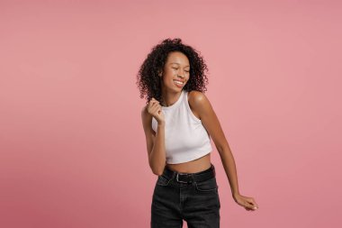 Pembe arka planda yalnız hareket eden gülümseyen Afro-Amerikan kadın portresi. Yaşam tarzı kavramı