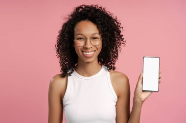 Pembe arka planda cep telefonu olan güzel bir Afro-Amerikan kadın portresi. Reklam, iş, teknoloji kavramı