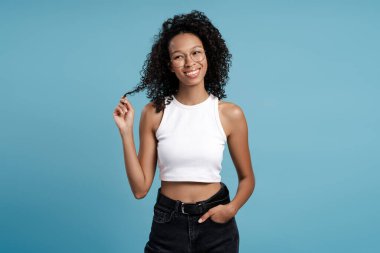 Mavi arka planda, stüdyoda poz veren gülümseyen Afro-Amerikan kadının portresi. Reklam, alışveriş konsepti