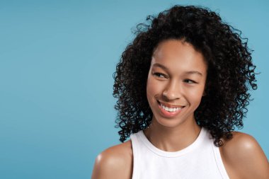 Mavi arka planda poz veren mutlu Afro-Amerikan kadın portresi, boşluğu kopyalamak istiyor. Reklam, alışveriş konsepti