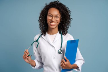 Beyaz önlüklü ve steteskoplu Afrikalı kadın doktor portresi. Elinde dosya var, izole edilmiş. Sağlık hizmeti, tıp konsepti