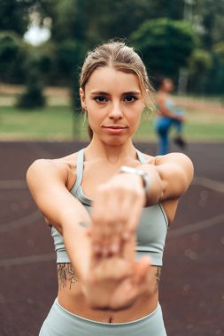 Çekici, beyaz kadın portresi spor giysisi giyiyor, ısınıyor, kameraya bakıyor, sokakta antrenman yapıyor. Spor yapan bir sporcu. Egzersiz konsepti