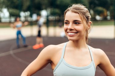 Gülümseyen, mutlu beyaz kadın portresi şık bir spor giysi giymiş gözlerini kaçırıyor, parkta, dışarıda antrenman yapıyor. Güzel bir atlet pozu. Spor konsepti