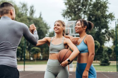 Gülümseyen, mutlu, çok uluslu kadınlar ve erkek tokalaşması. Açık hava eğitiminden sonra. Genç arkadaşlar birlikte çalışırlar. Spor konsepti