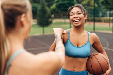 Mutlu, gülümseyen Afro-Amerikan kadın portresi spor giysisi giyiyor, top tutuyor, yumruk tokuşturuyor, birlikte antrenman yapıyorlar. Takım çalışması konsepti