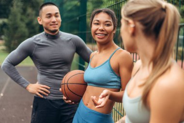 Çok ırklı kadın ve erkek giyimli bir grup spor giyer, konuşur, dışarıda birlikte antrenman yaparlar. Mutlu arkadaşlar, takım çalışması. İletişim. motivasyon kavramı