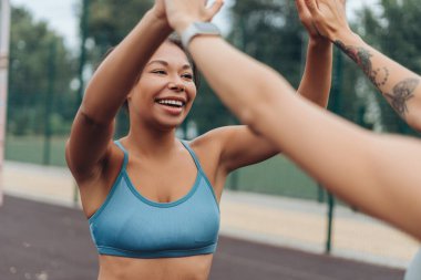 Heyecanlı, gülümseyen, mutlu, şık spor giyimli Afro-Amerikan bir kadının sokakta beşlik çakışının portresi. Eğitim, spor konsepti