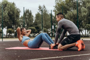 Aktif Afrikalı Amerikalı kadın portresi. Sokakta, dışarıda kişisel antrenörle karın kası eğitimi alıyor. Sağlıklı yaşam tarzı kavramı