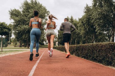 Arka plan, şık spor giysiler giyen etkin çok uluslu insanlar parkta, çapraz, kardiyo eğitiminde birlikte koşuyorlar. Sağlıklı yaşam tarzı kavramı