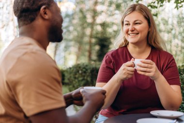 Gülümseyen beyaz kadın kafede buluşurken bir erkekle kahve içiyor.