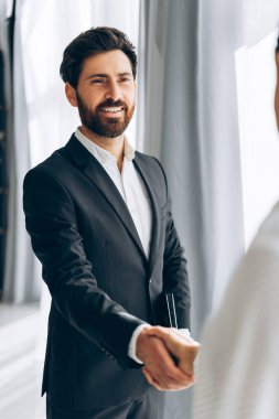 Yakışıklı, gülümseyen iş adamının portresi, sakallı İspanyol adamın el sıkışması, modern ofiste başarılı bir anlaşma. Buluşma konsepti