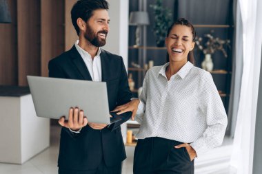 İş yerinde çalışan, dizüstü bilgisayar kullanan, modern ofiste proje planlayan çekici gülümseyen iş adamlarının portresi. Teknoloji konsepti, başarılı iş