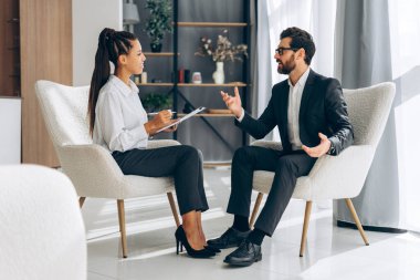 Gülümseyen, profesyonel psikiyatrist, hastayla konuşan doktor, sakallı İspanyol adam, modern ofiste iletişim. Terapi konsepti, akıl sağlığı